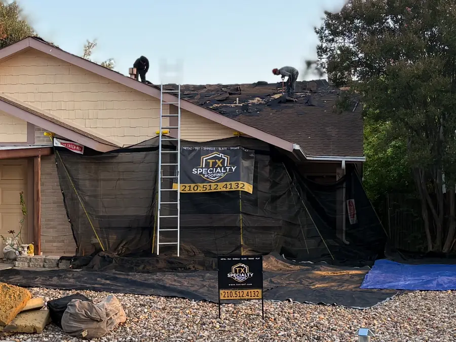 Crew tearing off an old shingle roof with Catch-All debris netting covering the walls and yard to catch nails and debris