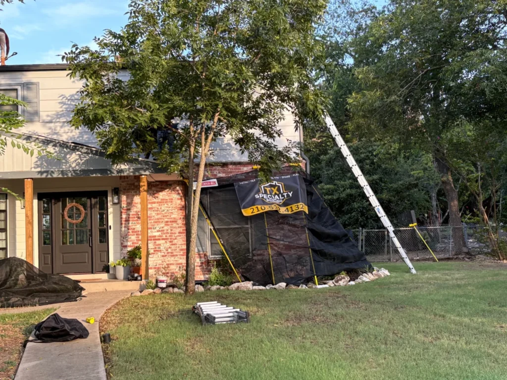 Front of a brick home with Catch-All netting protecting the entry and landscaping during a roof replacement
