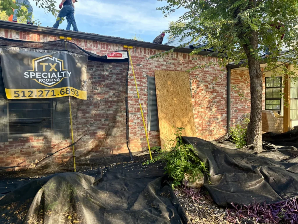 Catch-All netting and ground covers protecting the landscaping around a brick home while the crew works on the roof