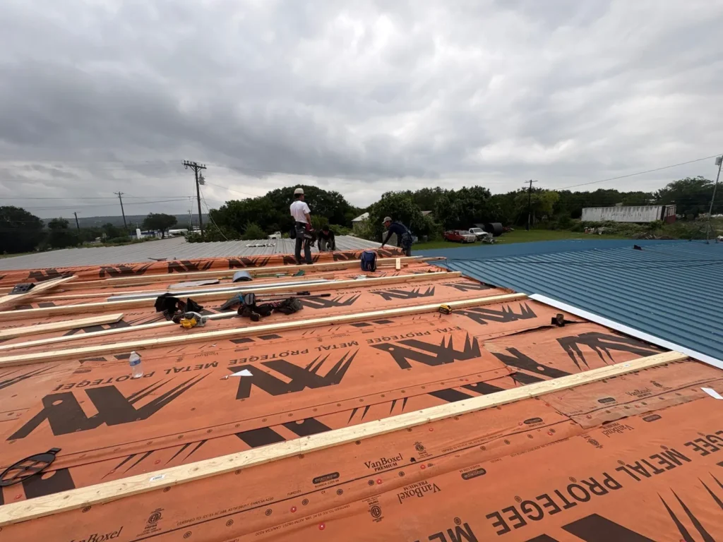 Synthetic underlayment and wood purlins installed over the flat roof section before the new metal panels in Burnet, TX