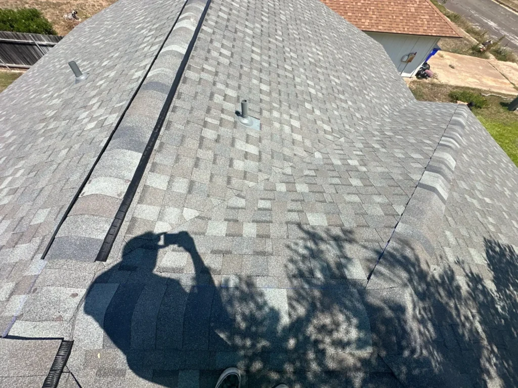 View along the new ridge vent and architectural shingles of a completed roof replacement in Cedar Park, TX