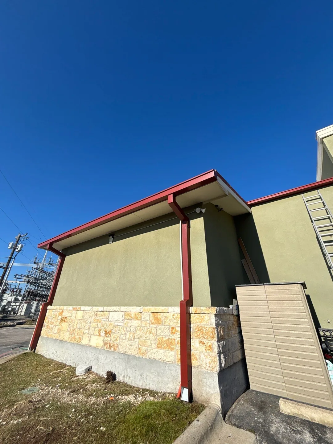 Custom 6-inch red commercial gutters and downspouts on a stucco and stone restaurant building
