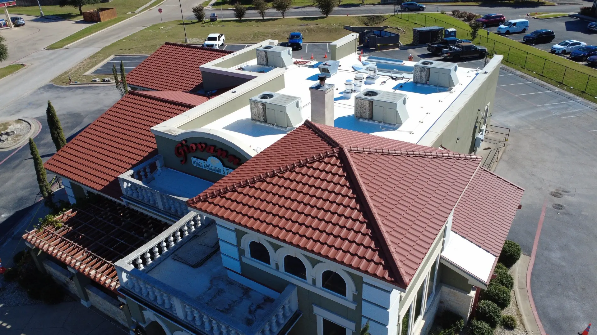 Giovanni's Italian Restaurant with a new Mediterranean-style metal tile roof, white PVC flat roof, and parapet coping