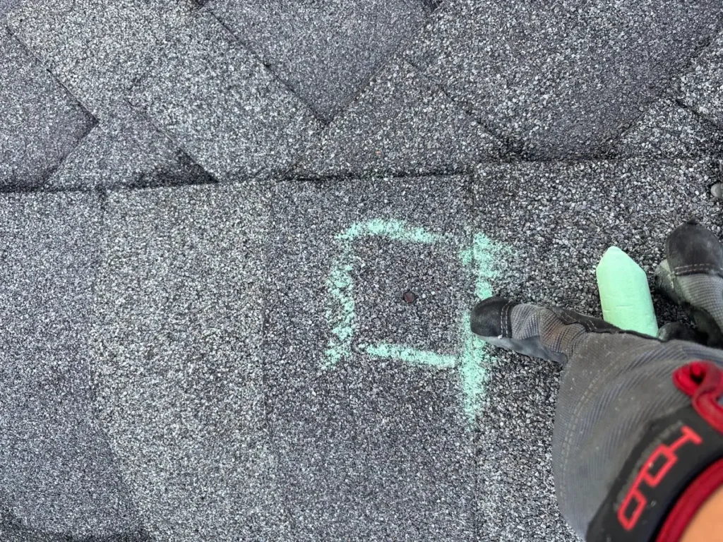 Green chalk box highlighting a small shingle damage point during roof inspection documentation.