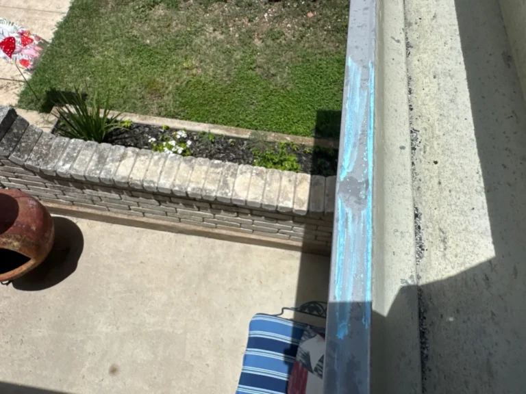 Hail dents marked in chalk on an aluminum gutter during a roof inspection in Helotes