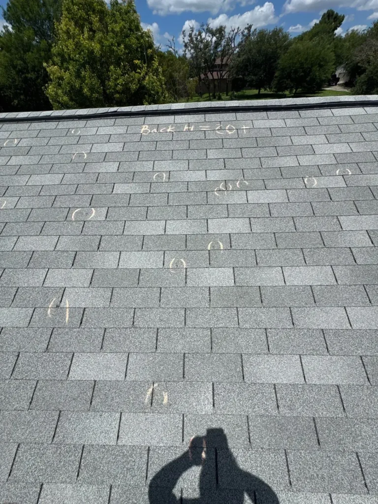 Roof slope with more than 20 hail hits circled in chalk during a Helotes hail damage inspection