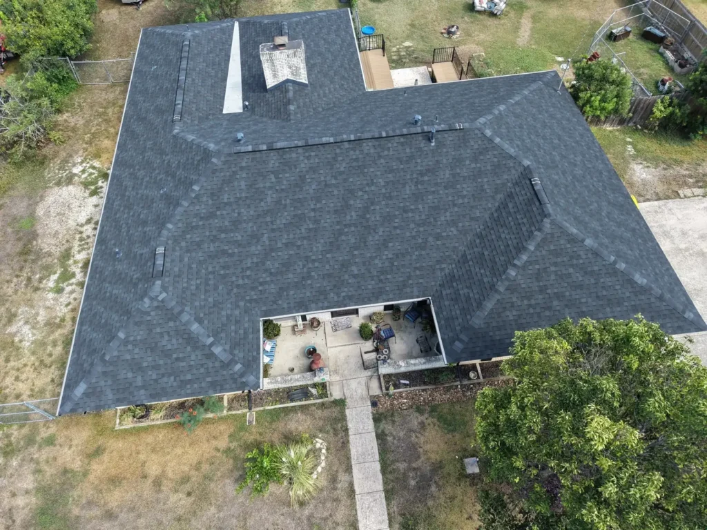 Wide aerial view of a Helotes property with a newly replaced shingle roof following hail damage