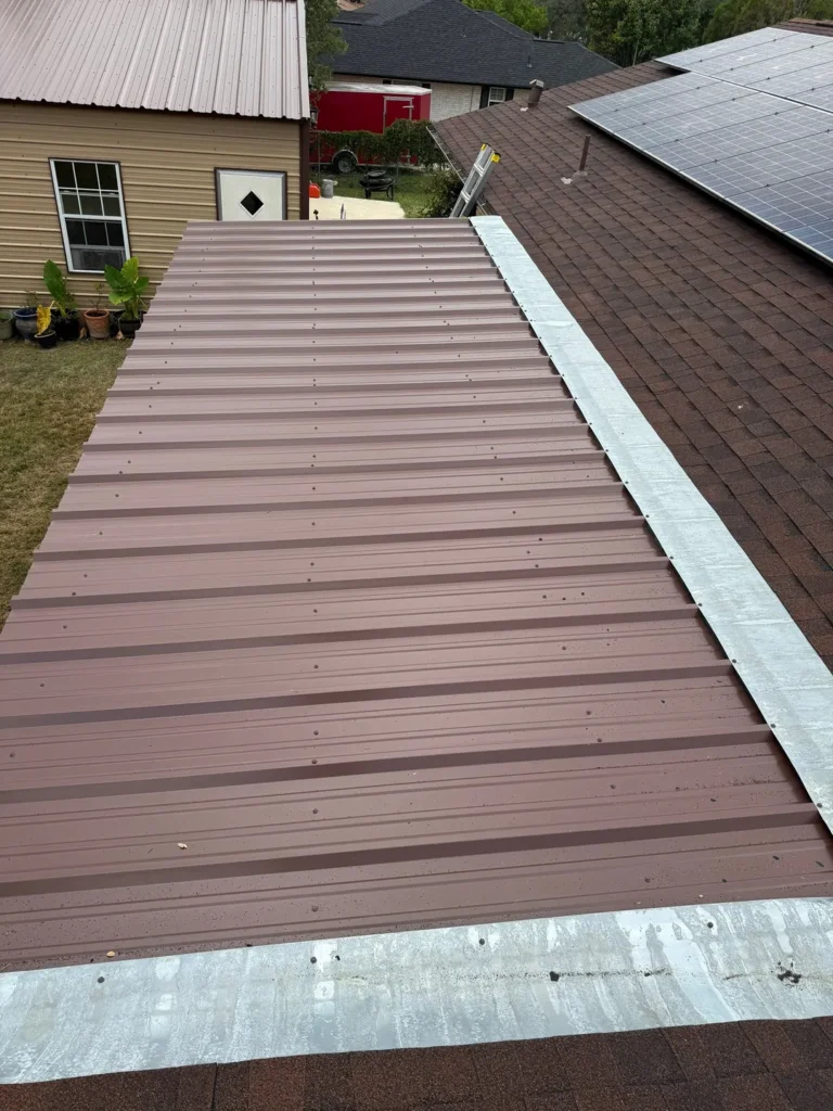 New brown corrugated metal patio roof with galvanized flashing tied into the shingle roof of a Helotes, TX home