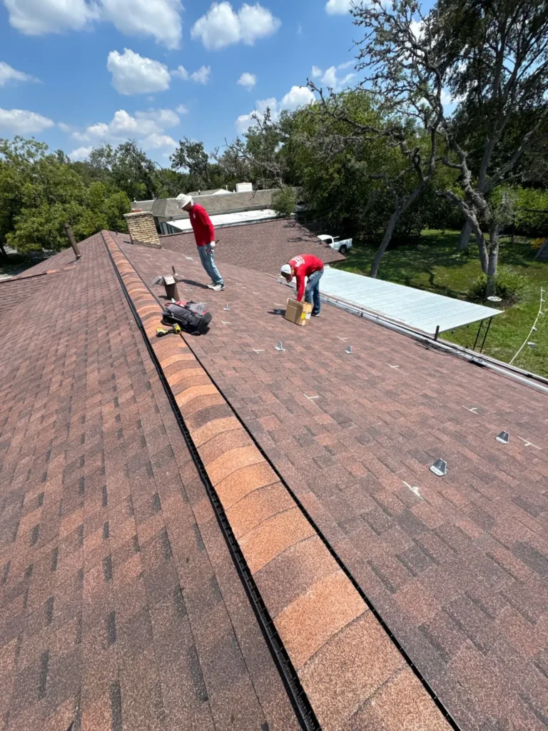 Solar crew installing flashed solar panel mounts on a new shingle roof in Helotes, TX
