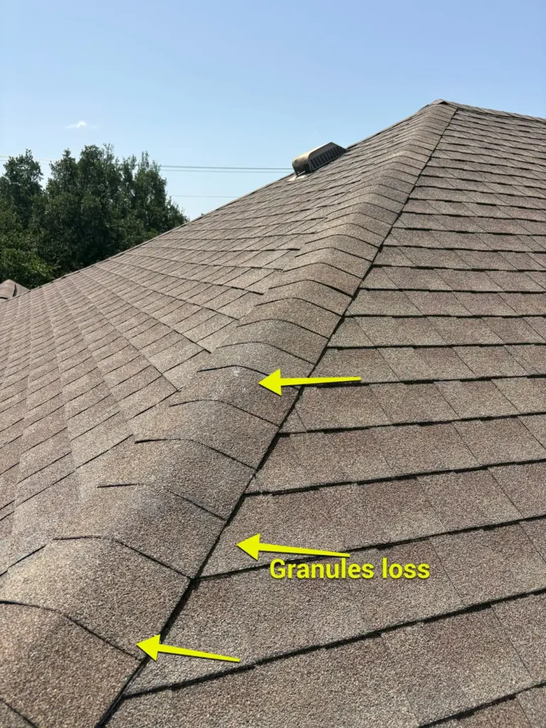 Hip cap shingles with patchy granule loss marked by arrows on a Liberty Hill home