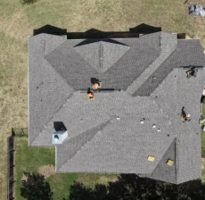Aerial view of a new shingle roof on a Liberty Hill, TX home as the crew installs the final ridge vents