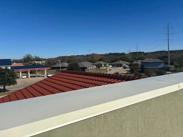 New metal coping capping a stucco parapet wall beside a finished metal tile roof on a commercial building