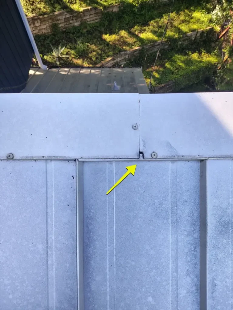 Arrow marking a gap at a fastener on a metal roof panel during an inspection