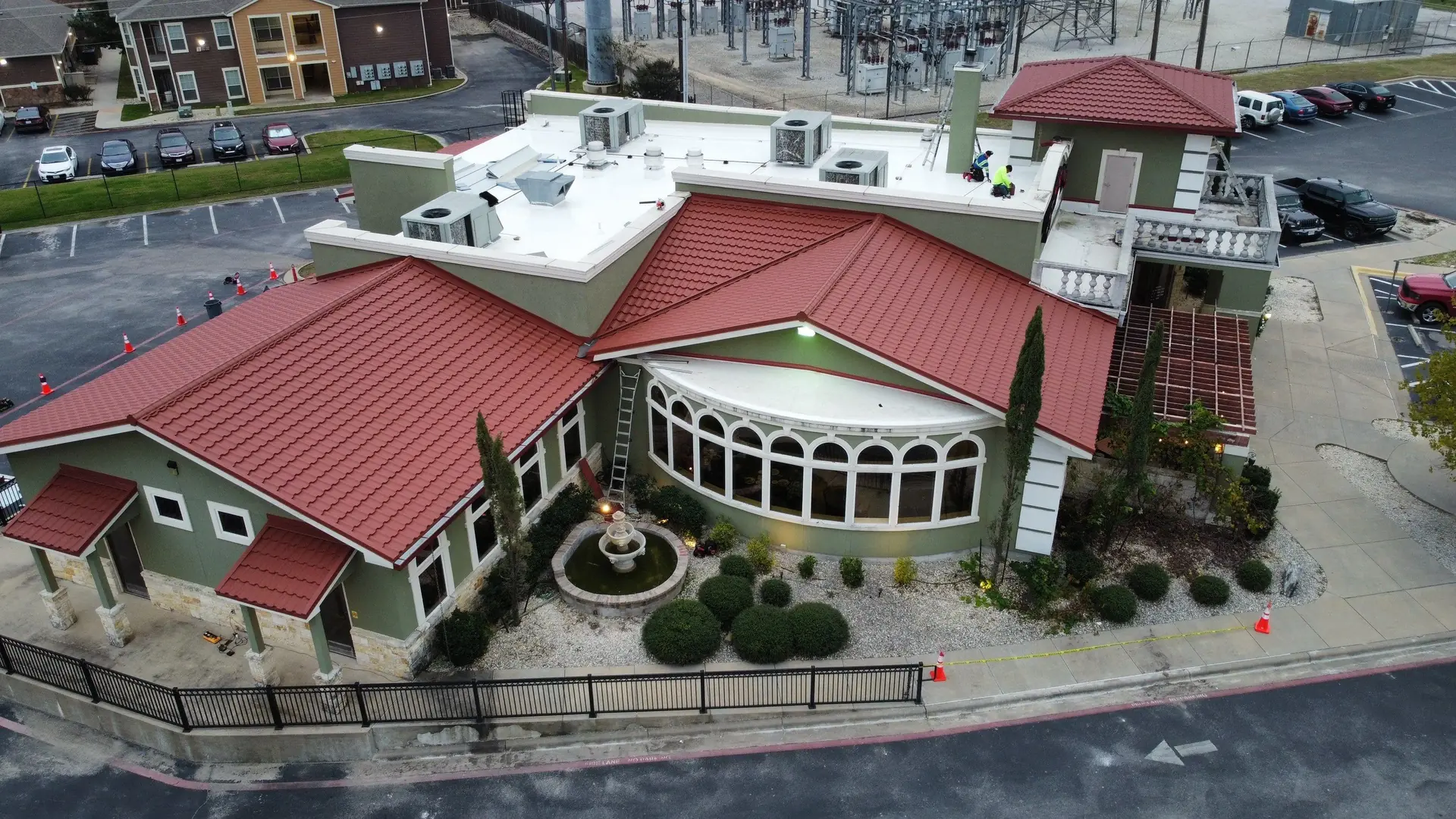 Restaurant with new metal tile hip and gable roofs, a curved white membrane roof over arched dining room windows, entry awnings, and a tower roof