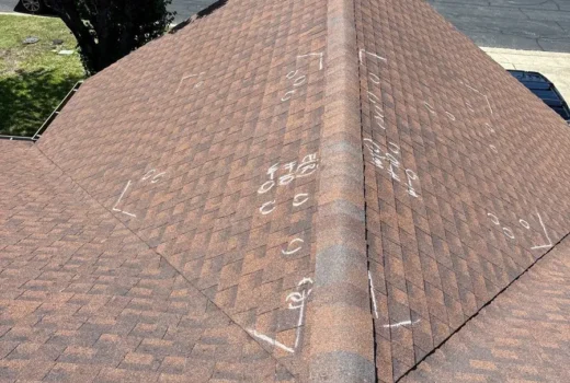 Wide roof view showing multiple chalk markings documenting damaged asphalt shingles during an inspection.