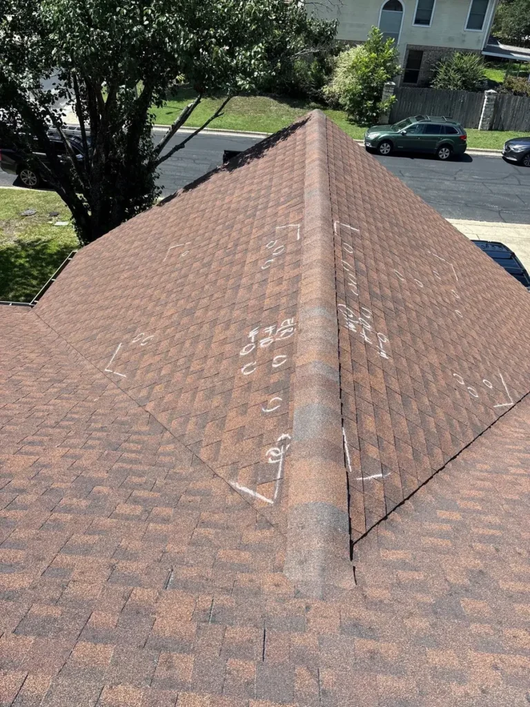 Wide roof view showing multiple chalk markings documenting damaged asphalt shingles during an inspection.