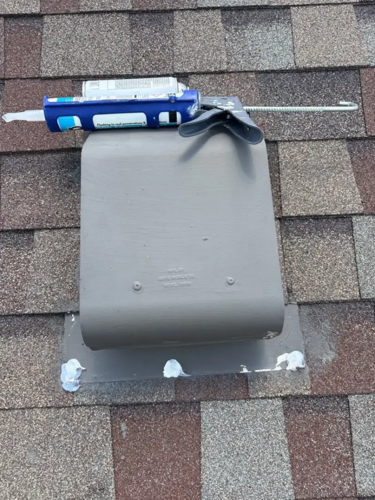 Roof vent being resealed with a caulk gun on an asphalt shingle roof