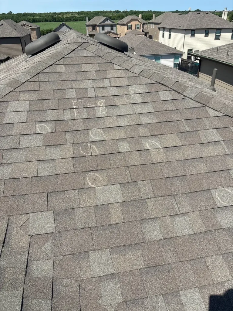 Hail hits circled in chalk inside a test square marked F=8 on the front slope of a roof in Uhland, TX