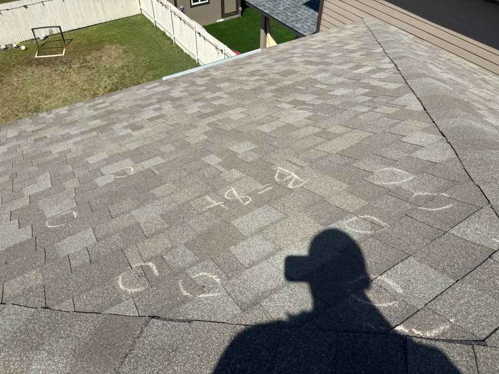 ear roof slope marked B=8+ with hail impacts circled in chalk during a hail damage inspection in Uhland, TX